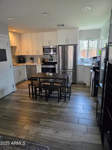 a kitchen with stainless steel appliances a refrigerator a stove a sink a dining table and chairs