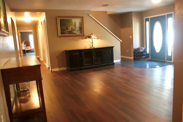 a view of a hallway with wooden floor fireplace and a kitchen space