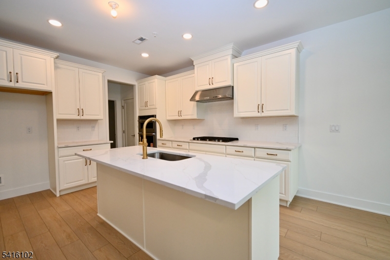 26 Arowana Road Randolph, NJ 07869 - Photo 8 of 26 a kitchen with kitchen island a sink a stove a refrigerator and white cabinets with wooden floor