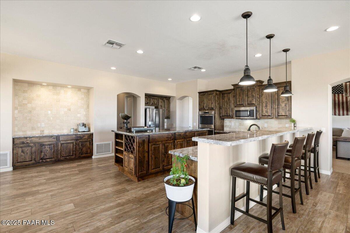 12300 West Slate Road Prescott, AZ 86305 - Photo 10 of 59 a kitchen with stainless steel appliances kitchen island granite countertop a table chairs and a refrigerator