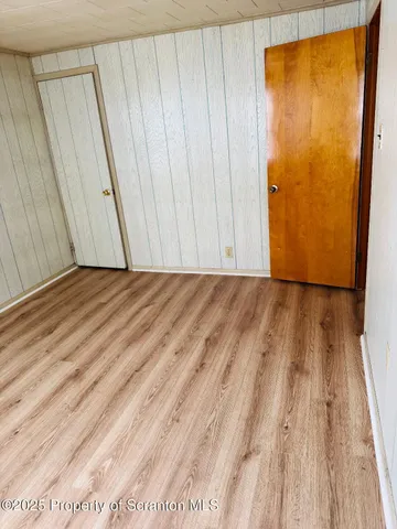 a view of a room with wooden floor and a door