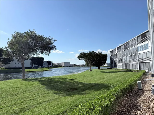 a view of a big house with a big yard and potted plants and large trees