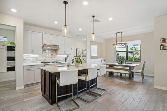 a kitchen with kitchen island granite countertop a sink dining table chairs and white cabinets