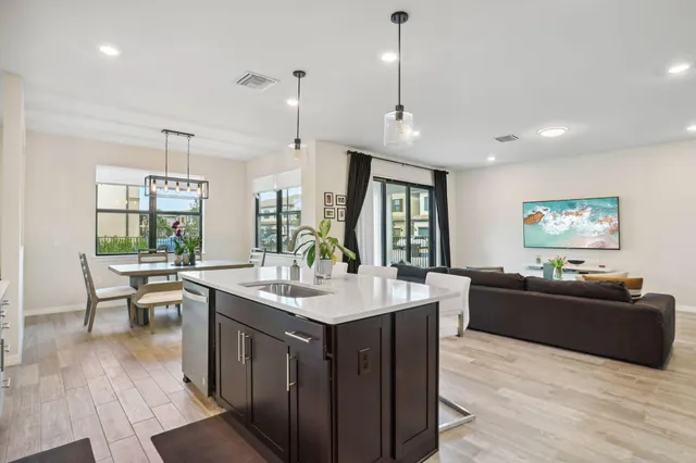 a living room with stainless steel appliances kitchen island granite countertop a sink a counter space and living room view