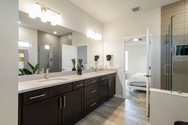 a en suite bathroom with a double vanity sink a large mirror and shower