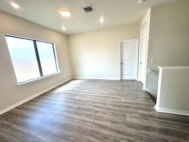a view of empty room with wooden floor and fan