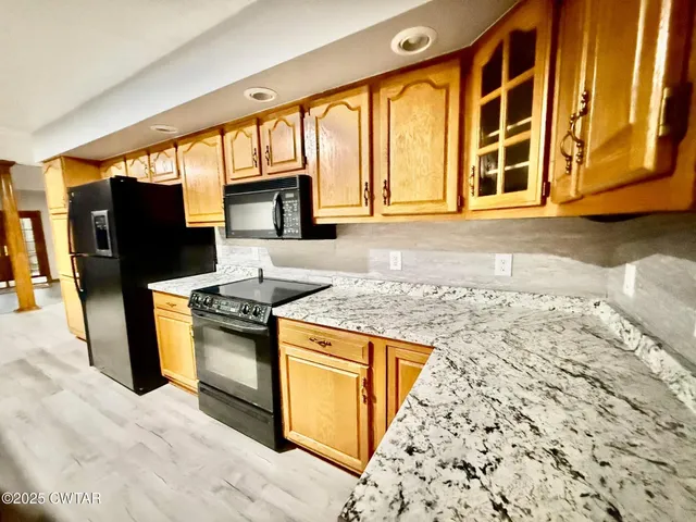 a kitchen with granite countertop a stove a sink and a refrigerator