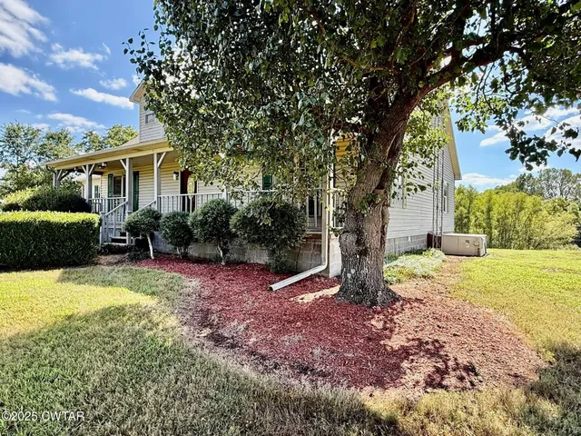 a view of a house with backyard and a tree