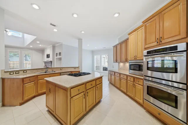 a kitchen with stainless steel appliances granite countertop a stove top oven a sink dishwasher and a microwave oven with large trees