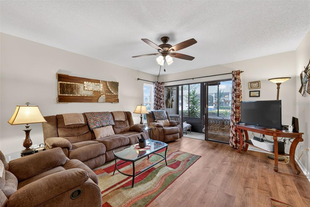 1258 Pine Ridge Circle West, Unit D1 Tarpon Springs, FL 34688 - Photo 12 of 42 a living room with furniture a ceiling fan a flat screen tv and a window
