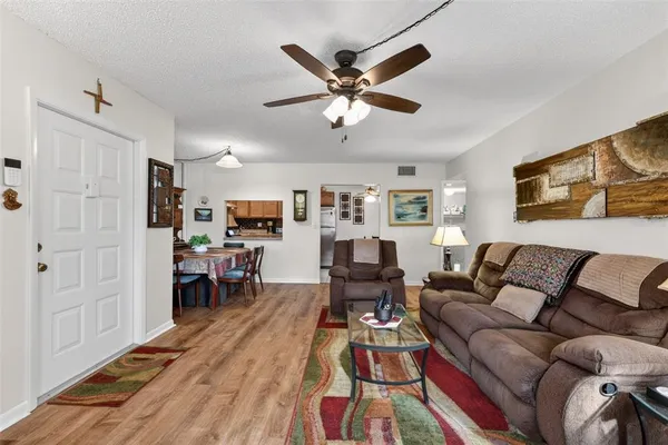 a living room with furniture a chandelier fan and a window