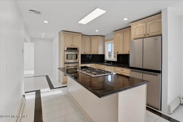 a kitchen with stainless steel appliances kitchen island granite countertop a refrigerator and a stove top oven