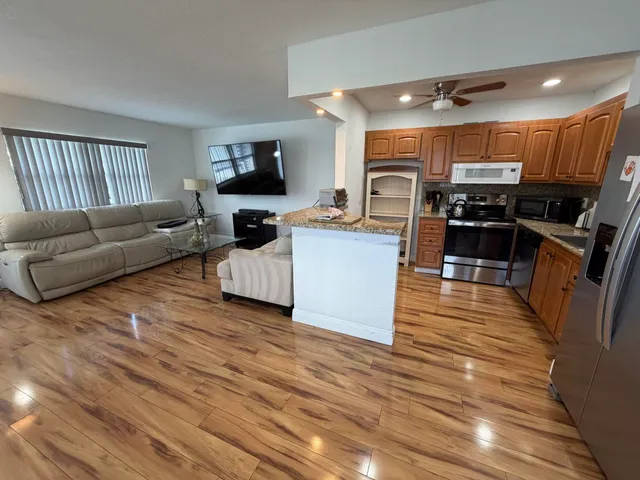 a living room with furniture kitchen view and a wooden floor