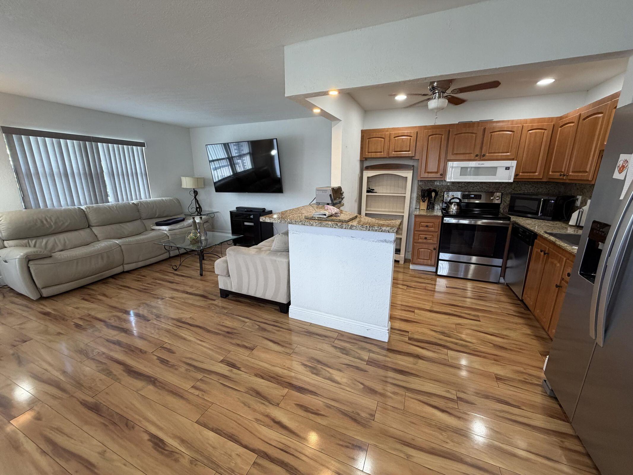 a living room with furniture kitchen view and a wooden floor