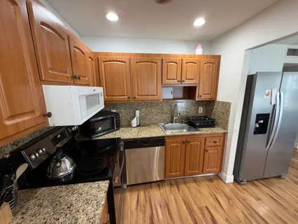 a kitchen with stainless steel appliances granite countertop a refrigerator a sink and wooden cabinets