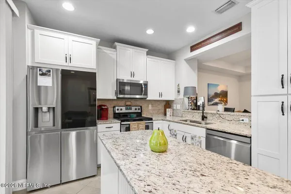 a kitchen with stainless steel appliances kitchen island granite countertop a sink refrigerator and microwave