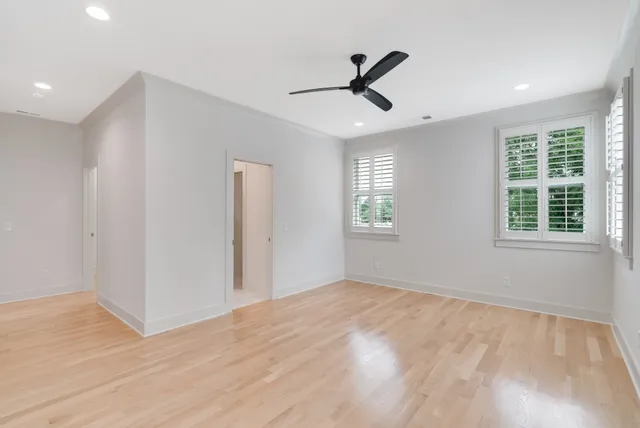 a view of empty room with wooden floor and fan