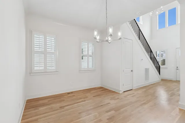 a view of a livingroom with wooden floor stairs and a chandelier