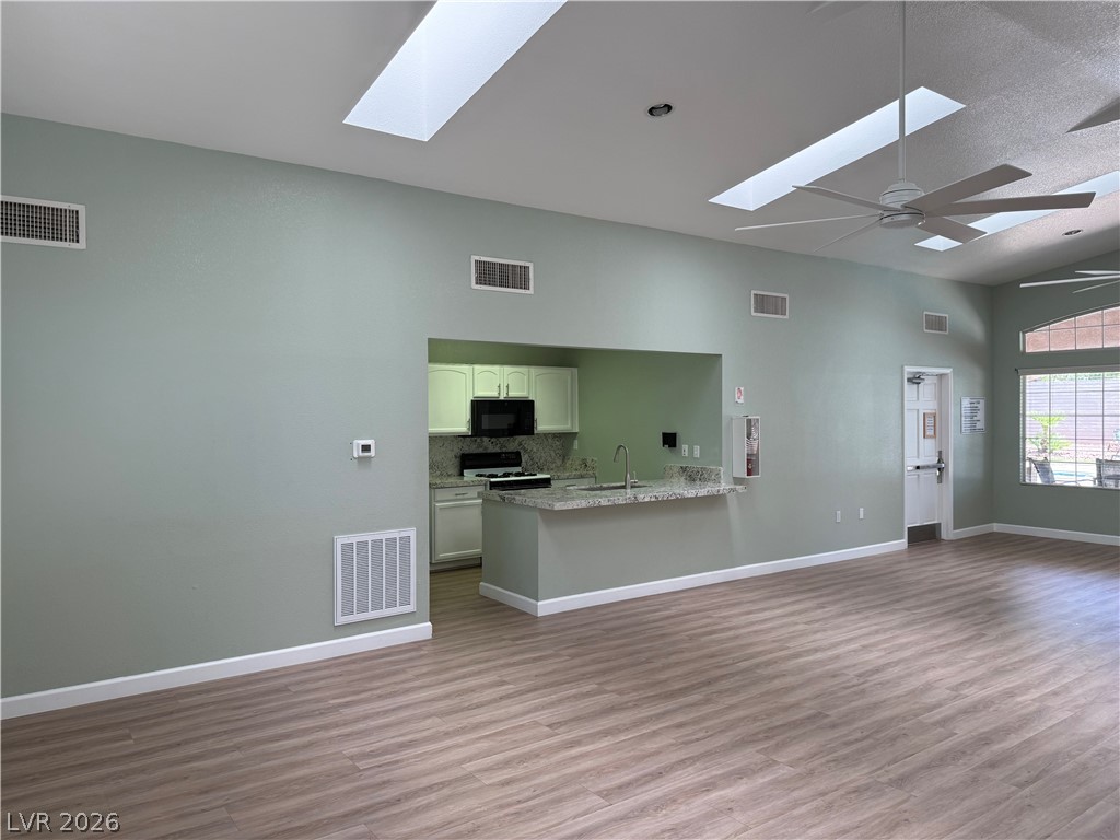 517 Crumpler Place Henderson, NV 89052 - Photo 9 of 9 An airy common room features sleek wood flooring and a convenient kitchen passthrough, bathed in natural light from multiple skylights.