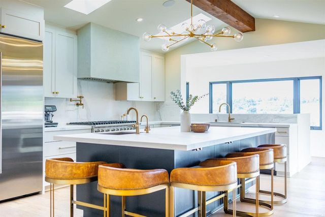 a kitchen with stainless steel appliances granite countertop a sink a stove and chairs