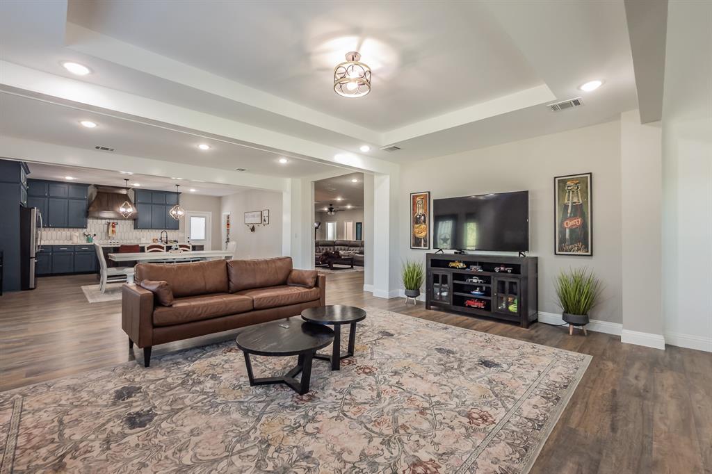 117 Rock Salt Drive Springtown, TX 76082 - Photo 11 of 38 Open-concept living area featuring wood-finish flooring, recessed lighting, and a tray ceiling