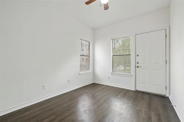 an empty room with wooden floor cabinet and windows