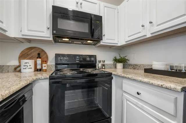 a kitchen with granite countertop a stove top oven microwave and cabinets