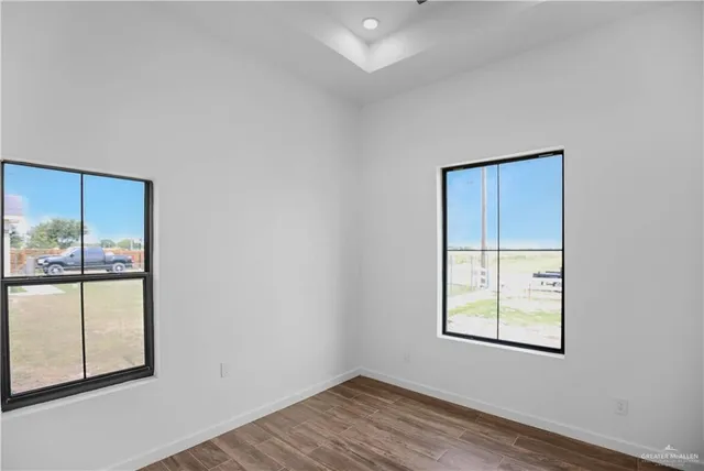 an empty room with wooden floor and windows