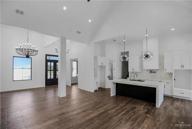 a large white kitchen with a refrigerator a sink dishwasher a stove and white cabinets with wooden floor