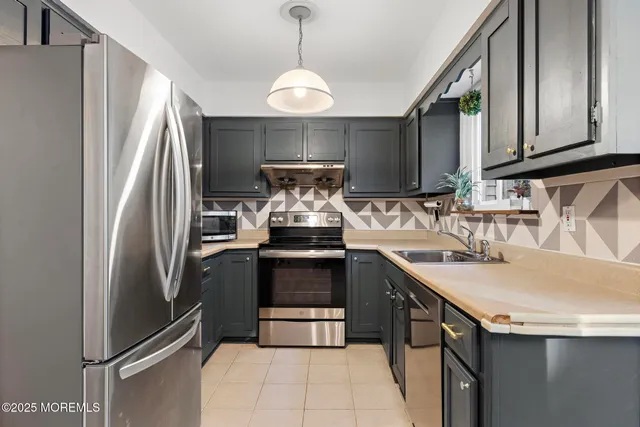 a kitchen with stainless steel appliances granite countertop a sink and a refrigerator