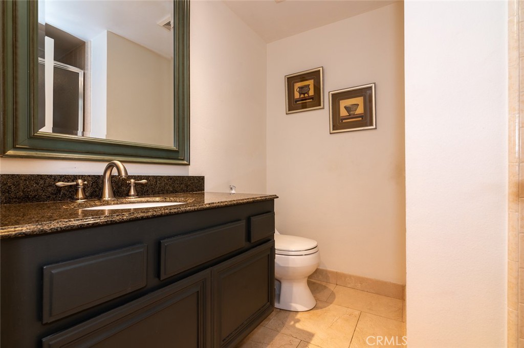 7117 Lonzo Street Tujunga, CA 91042 - Photo 27 of 49 a bathroom with a granite countertop toilet sink and mirror