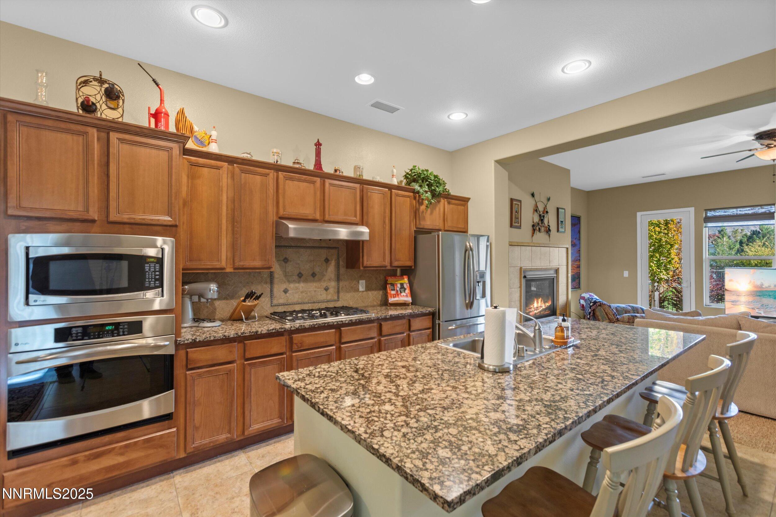 10900 Serratina Drive Reno, NV 89521 - Photo 7 of 47 a kitchen with stainless steel appliances kitchen island granite countertop a stove refrigerator and a microwave