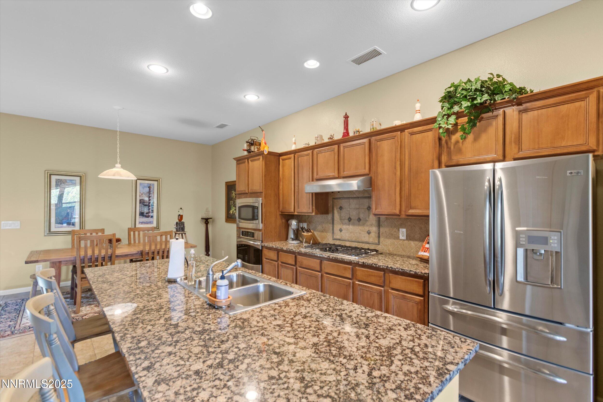 10900 Serratina Drive Reno, NV 89521 - Photo 9 of 47 a kitchen with stainless steel appliances granite countertop a refrigerator sink and cabinets