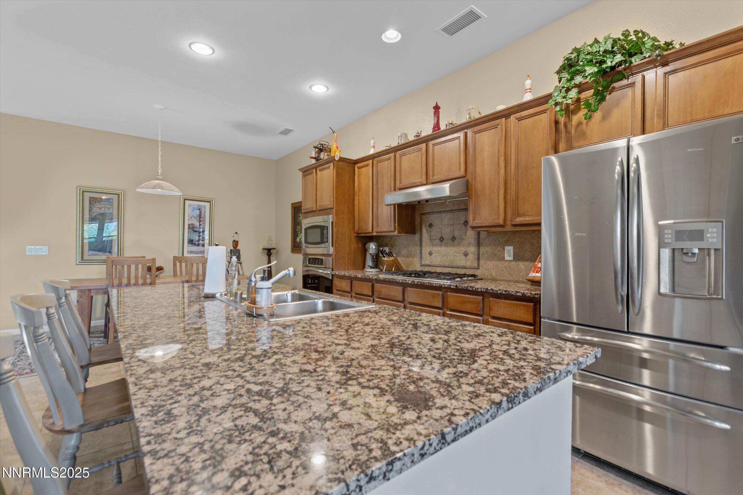 10900 Serratina Drive Reno, NV 89521 - Photo 10 of 47 a kitchen with stainless steel appliances granite countertop a refrigerator sink and stove