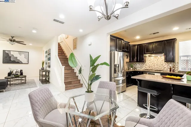 a living room with furniture kitchen view and a wooden floor