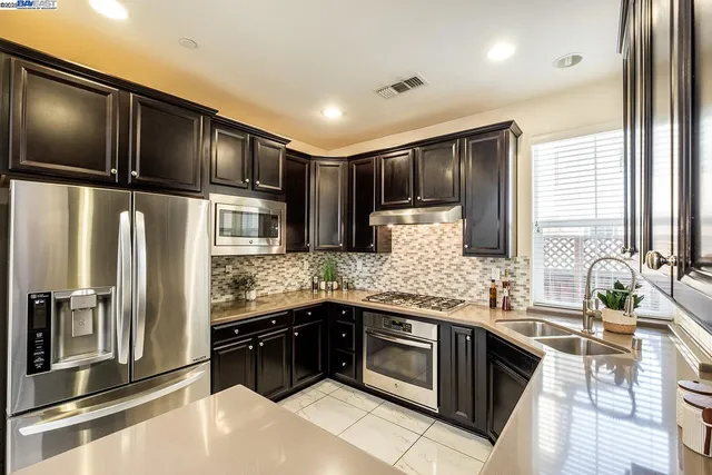 a kitchen with stainless steel appliances kitchen island granite countertop a refrigerator and a sink
