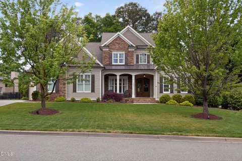 a front view of a house with a garden and trees
