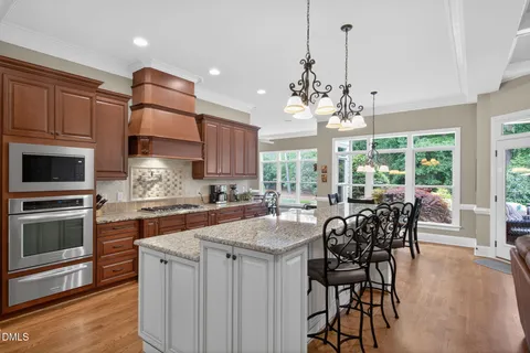 a kitchen with granite countertop a dining table chairs stainless steel appliances and cabinets