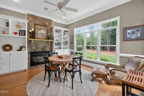 a kitchen with stainless steel appliances granite countertop a stove a refrigerator a kitchen island a dining table and chairs with wooden floor