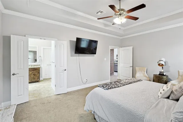 a bedroom with a bed a flat screen tv and a chandelier