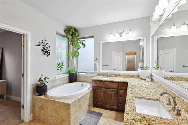 a bathroom with a granite countertop sink a toilet a mirror and bathtub