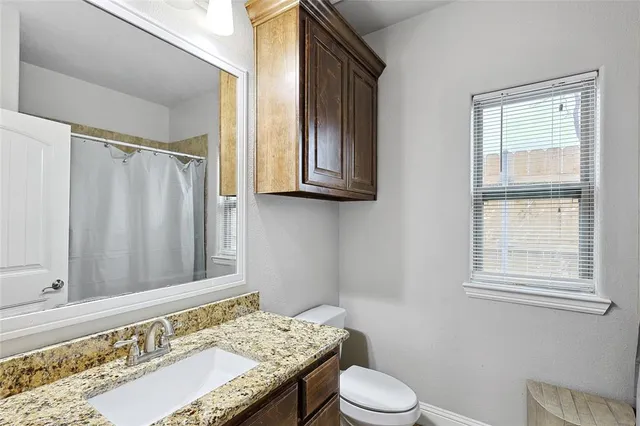 a bathroom with a granite countertop sink toilet and shower