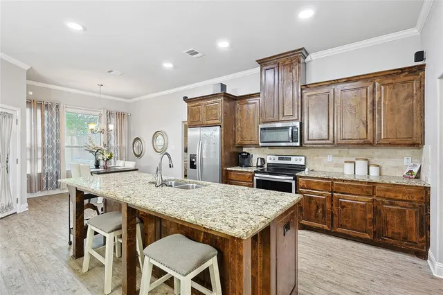 a kitchen with stainless steel appliances granite countertop a kitchen island hardwood floor sink stove dining table and chairs