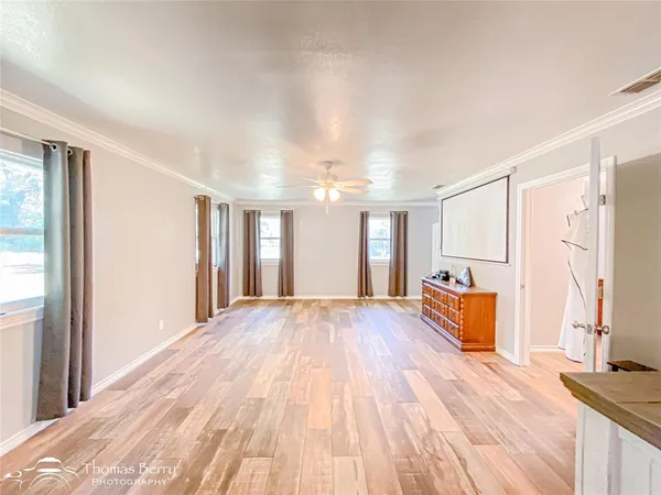 a view of empty room with wooden floor and fan