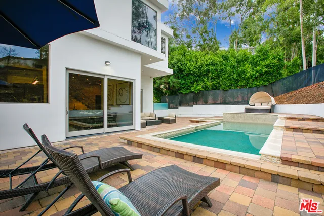 a view of a patio with table and chairs near a barbeque