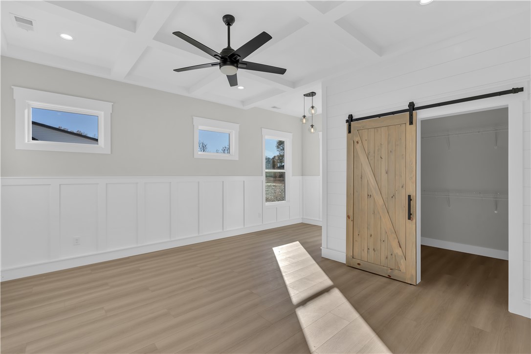 516 Lakeside Drive Anderson, SC 29621 - Photo 23 of 32 A spacious room features wainscoting and a distinctive coffered ceiling, highlighted by a modern ceiling fan and natural wood barn door.