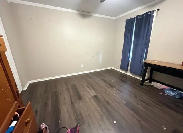 a view of an empty room with wooden floor and a window