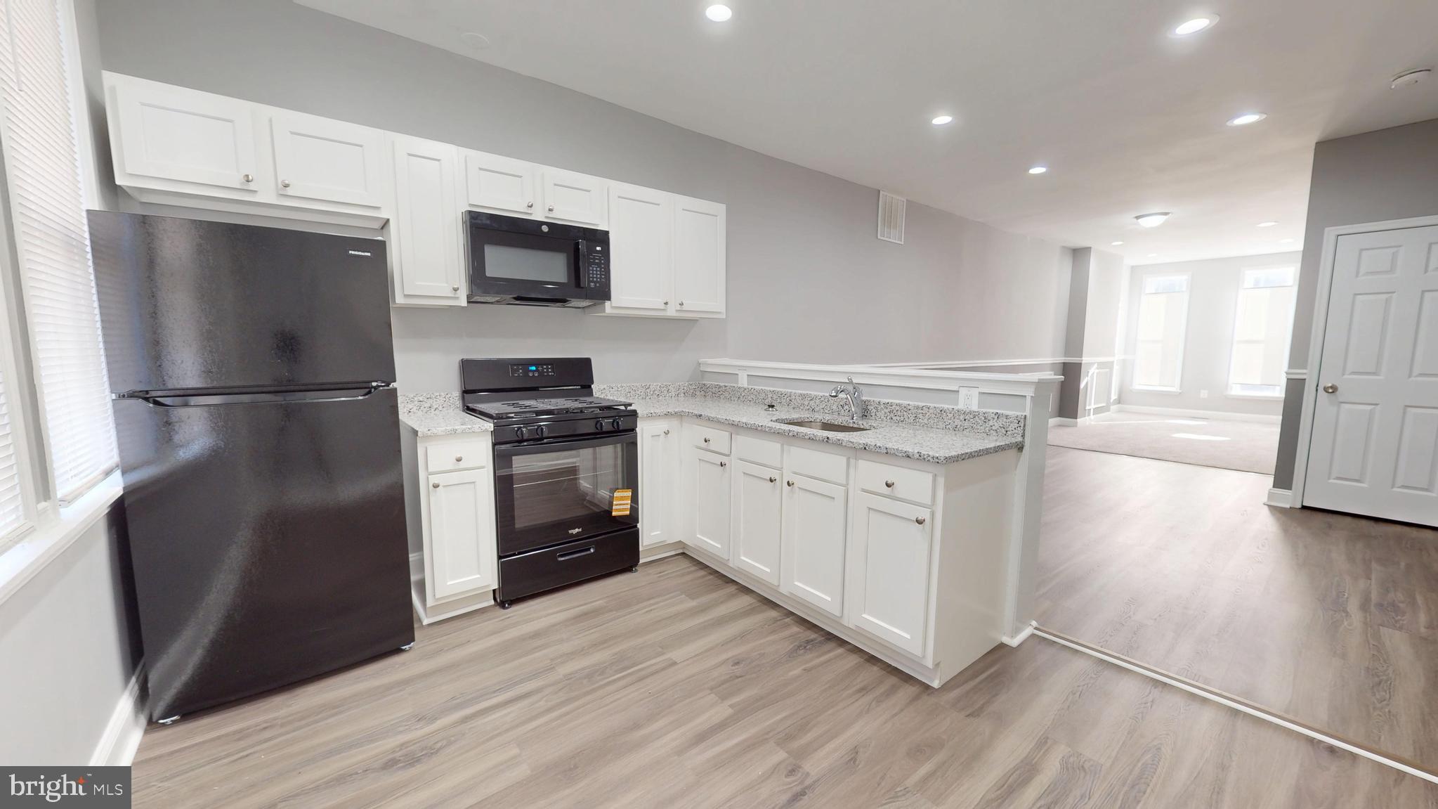 1824 Federal Street Baltimore, MD 21213 - Photo 7 of 17 a kitchen with a refrigerator stove and white cabinets