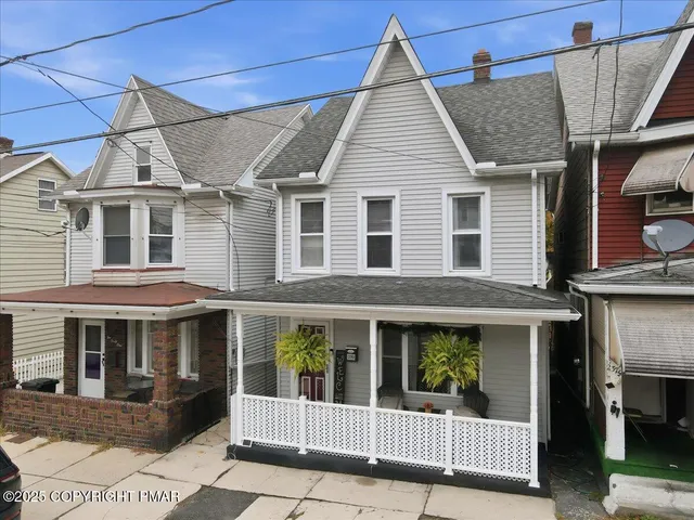 a view of a white house with large windows and a small yard