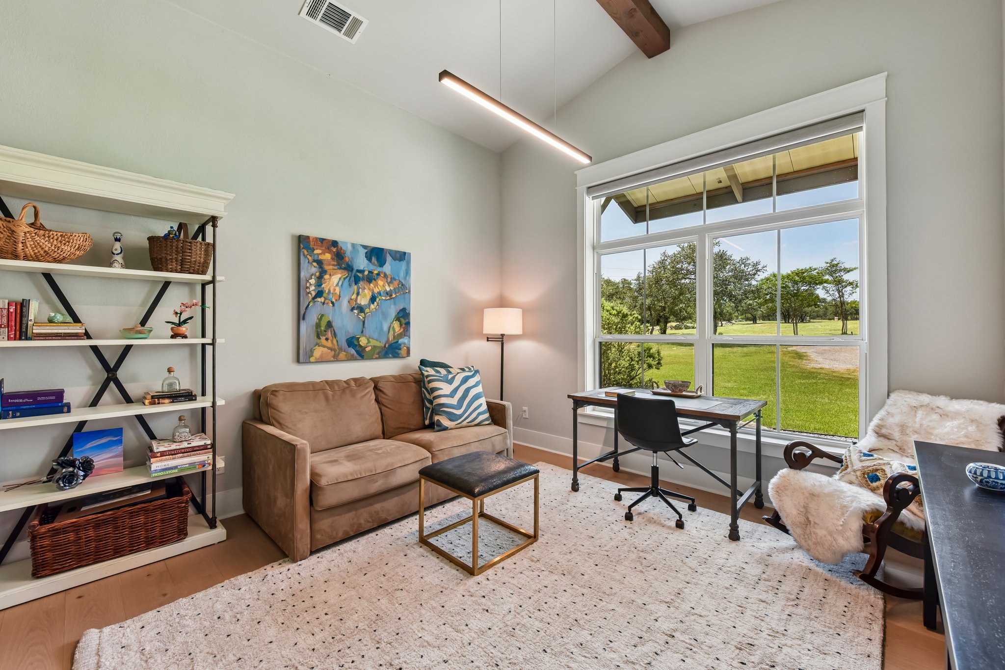 2203 Improver Road Spicewood, TX 78669 - Photo 18 of 38 A well-lit home office features hardwood floors, vaulted ceilings, and a large window overlooking a scenic green landscape.